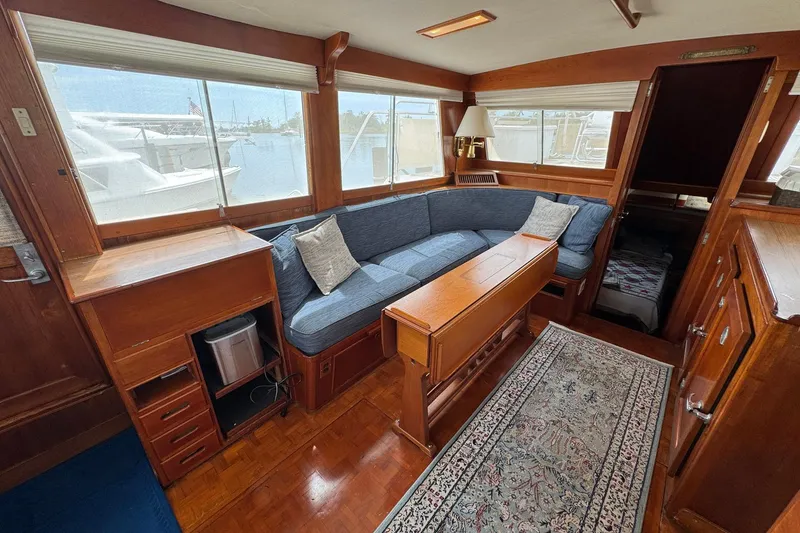 Slide: The Image of 1989 Grand Banks 42 Motor Yacht interior with wooden furnishings and blue cushioned seating. - 42