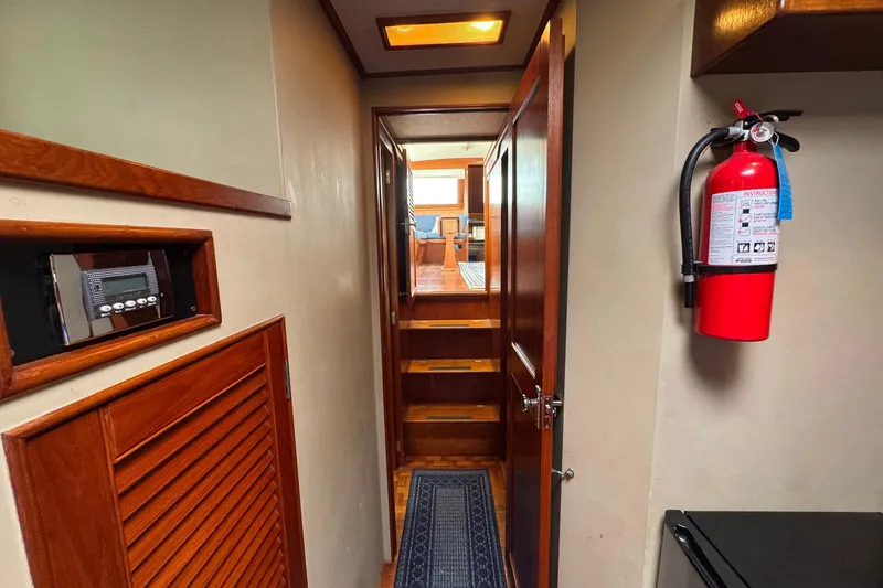 Slide: The Image of 1989 Grand Banks 42 Motor Yacht interior hallway with fire extinguisher and wooden accents. - 62