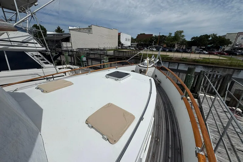 Slide: The Image of 1989 Grand Banks 42 Motor Yacht docked, showcasing spacious deck and classic wooden railings. - 9