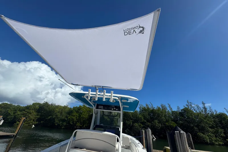 Slide: The Image of 2023 Sea Hunt Ultra 305 SE boat with sunshade, docked under clear blue sky. - 21