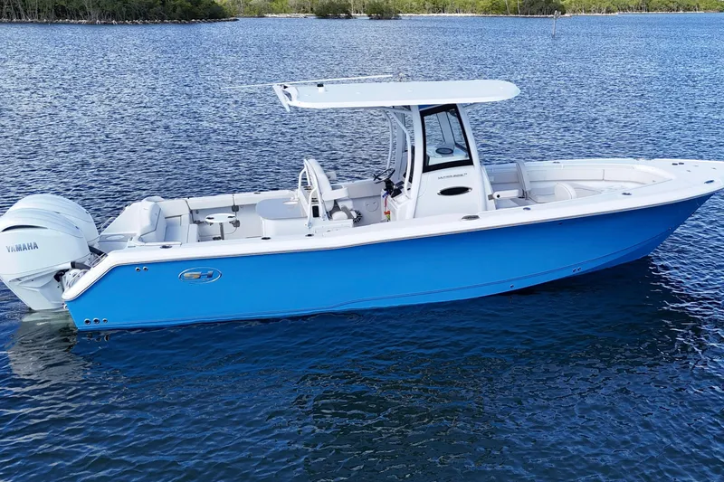 Slide: The Image of 2023 Sea Hunt Ultra 305 SE boat on calm water, featuring a sleek blue design. - 7