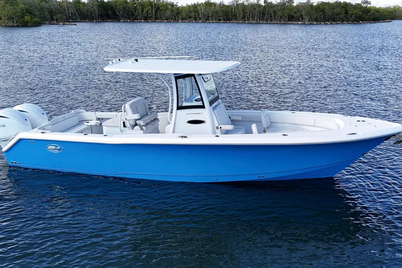 Slide: The Image of 2023 Sea Hunt Ultra 305 SE boat on calm water, featuring a sleek blue hull. - 9