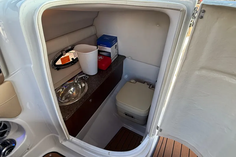 Slide: The Image of 2018 Crownline Eclipse E24 XS boat interior with sink, toilet, and storage space. - 32
