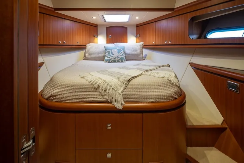 Slide: The Image of Luxurious 2015 Hampton motor yacht bedroom with elegant wood paneling and cozy bedding. - 49