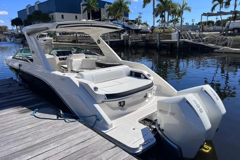 Slide: The Image of 2019 Sea Ray SLX 310 Outboard docked by waterfront with palm trees and blue sky. - 10
