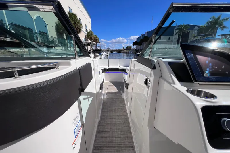 Slide: The Image of 2019 Sea Ray SLX 310 Outboard interior view with clear skies and marina backdrop. - 59