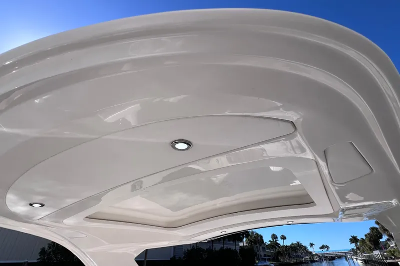 Slide: The Image of 2019 Sea Ray SLX 310 Outboard boat with sleek hardtop against a clear blue sky. - 72