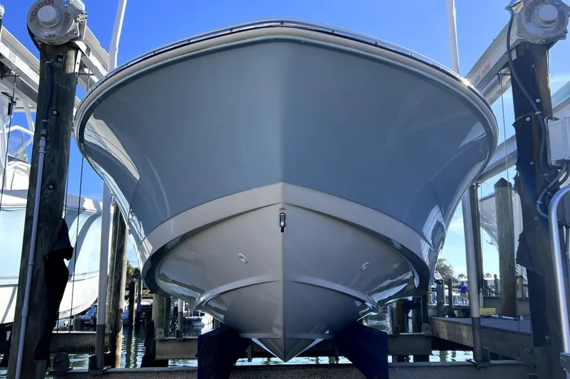 Slide: The Image of 2023 Boston Whaler 220 Dauntless boat cruising on a calm waterway under a clear blue sky. - 2