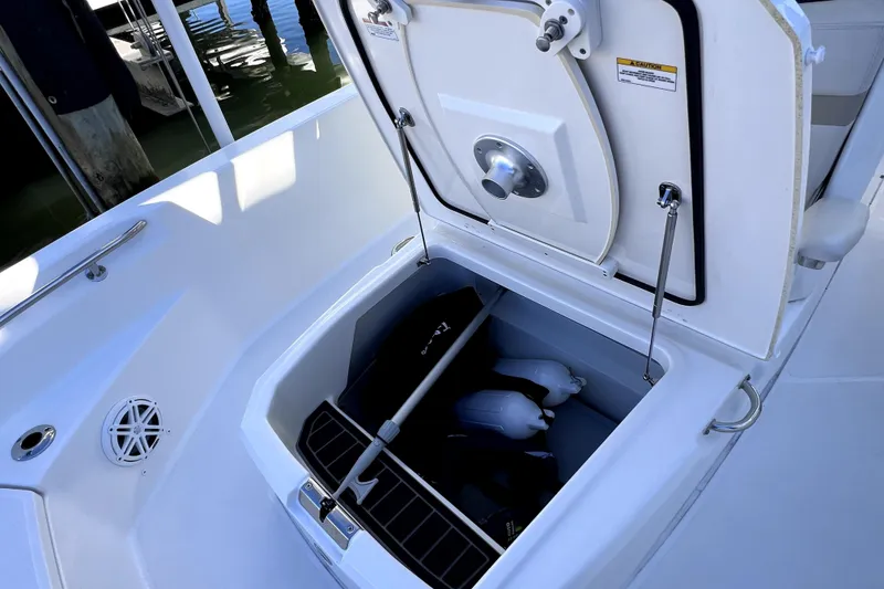 Slide: The Image of 2023 Boston Whaler 220 Dauntless storage compartment with open hatch and marine equipment. - 61
