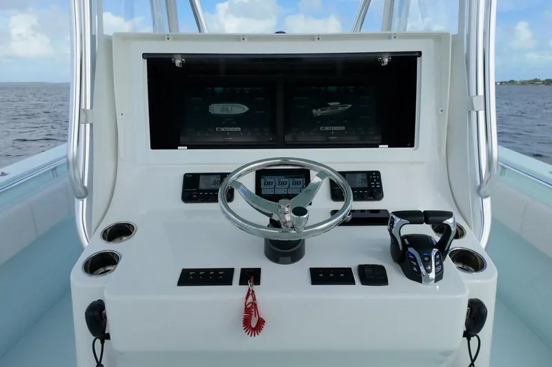 Slide: The Image of 2025 Contender 39 ST boat dashboard with steering wheel and electronic controls. - 14