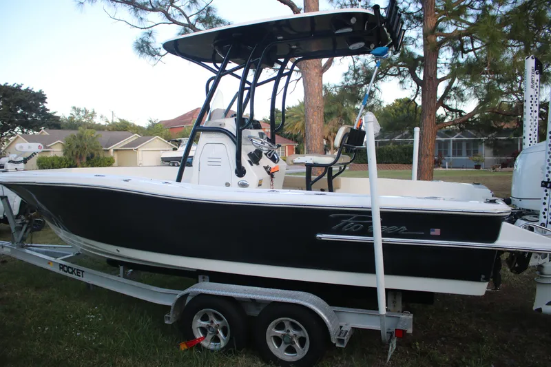 Slide: The Image of 2022 Pioneer 220 Bay Sport boat on trailer, parked outdoors near trees and houses. - 9
