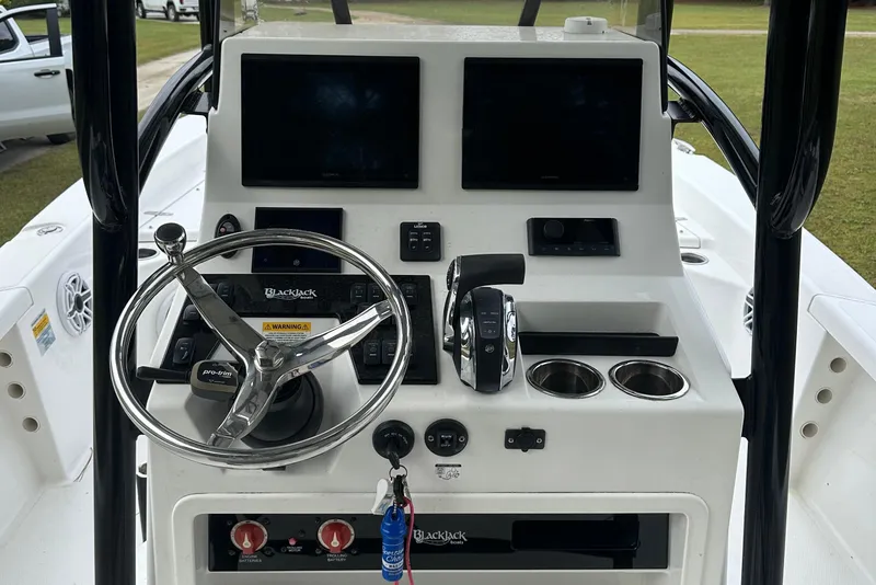 Slide: The Image of 2022 BlackJack 256 Bay boat console with steering wheel, controls, and dual cup holders. - 20