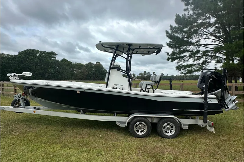 Slide: The Image of 2022 BlackJack 256 Bay boat on trailer, parked on grass under cloudy sky. - 3