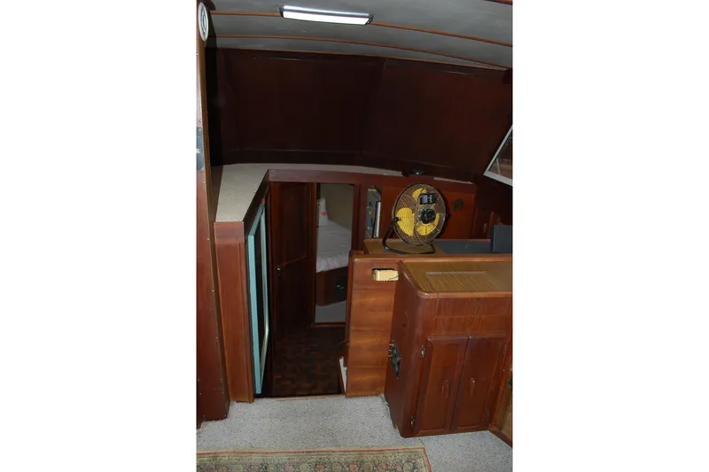Slide: The Image of 1987 Jersey Dawn boat interior with wooden cabinetry and fan, showcasing cozy cabin space. - 16