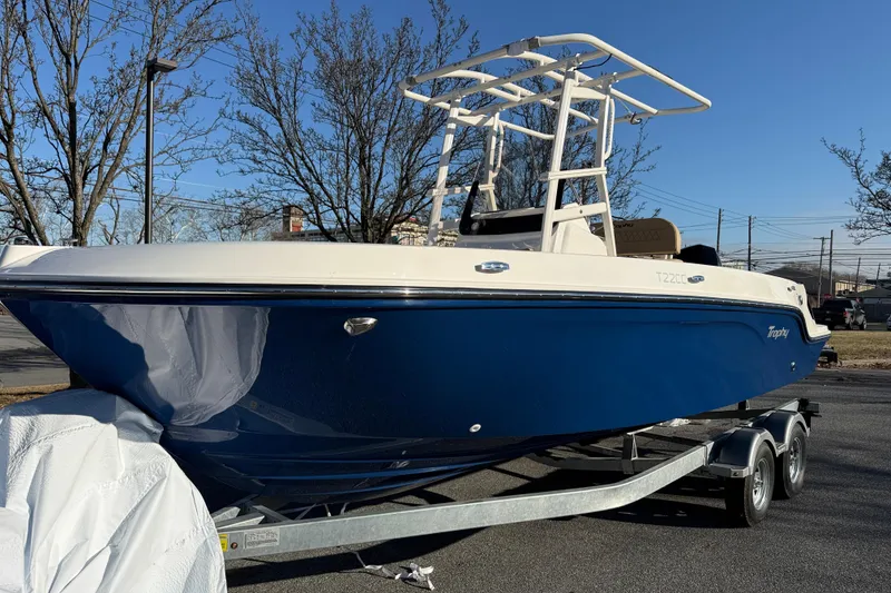 The Image of 2026 Bayliner Trophy T22CC boat on trailer, blue hull, parked outdoors. - 0