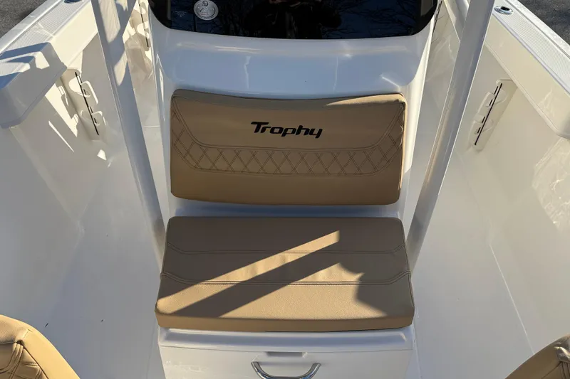 Slide: The Image of 2026 Bayliner Trophy T22CC boat seating area with beige cushions and "Trophy" logo. - 14
