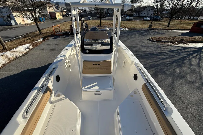 Slide: The Image of 2026 Bayliner Trophy T22CC boat interior with seating and console, parked outdoors. - 16