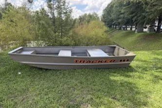 The Image of 2026 Tracker Grizzly 10 Jon boat on grassy area with trees in background. - 0