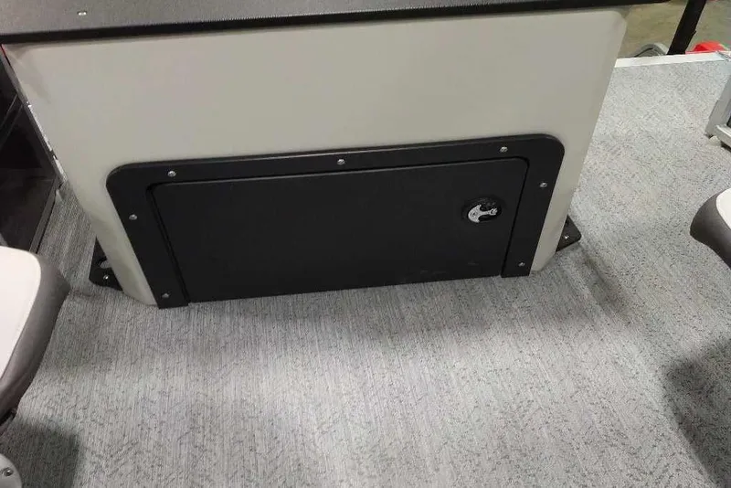 Slide: The Image of 2026 Sun Tracker Fishin' Barge 22 XP3 storage compartment on carpeted deck. - 116