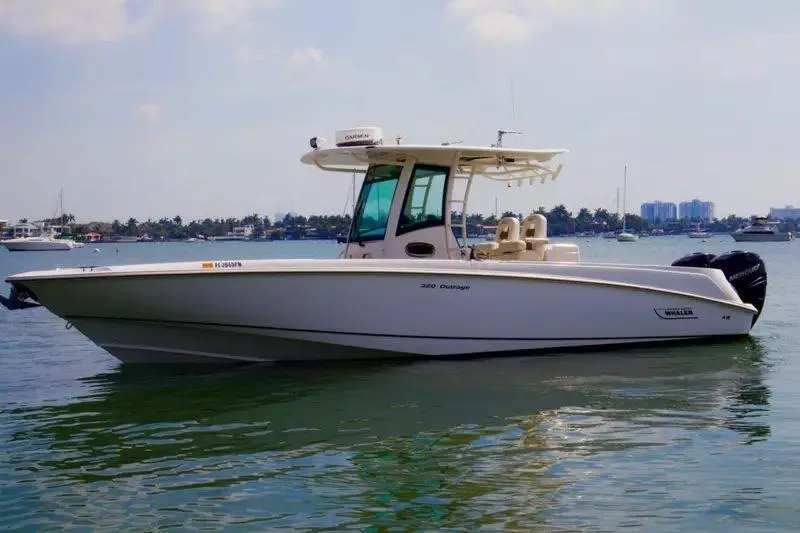 The Image of 2013 Boston Whaler 320 Outrage boat on calm water, clear sky background. - 1