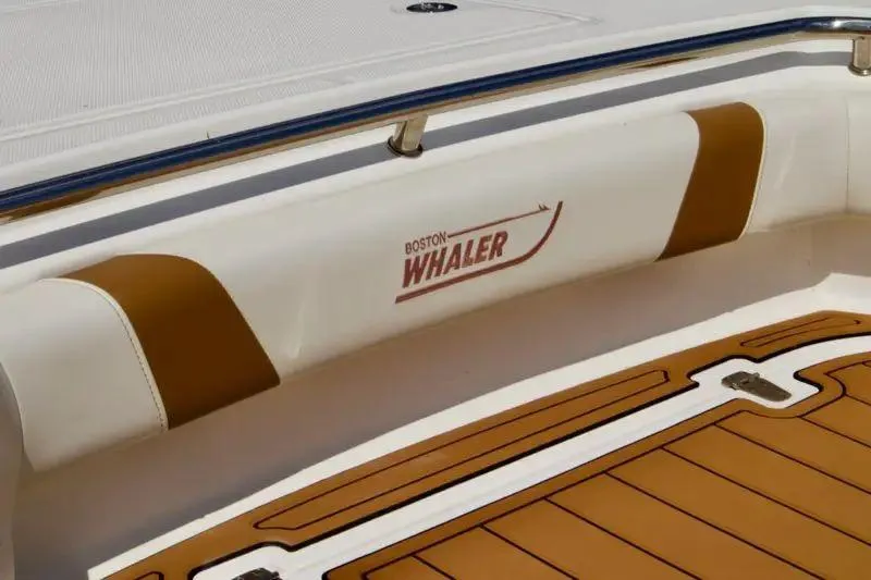 Slide: The Image of 2013 Boston Whaler 320 Outrage boat interior with logo and cushioned seating. - 9