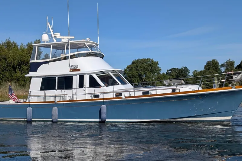 The Image of 2004 Grandbanks 58 Eastbay FB yacht on calm water, blue hull, American flag. - 1