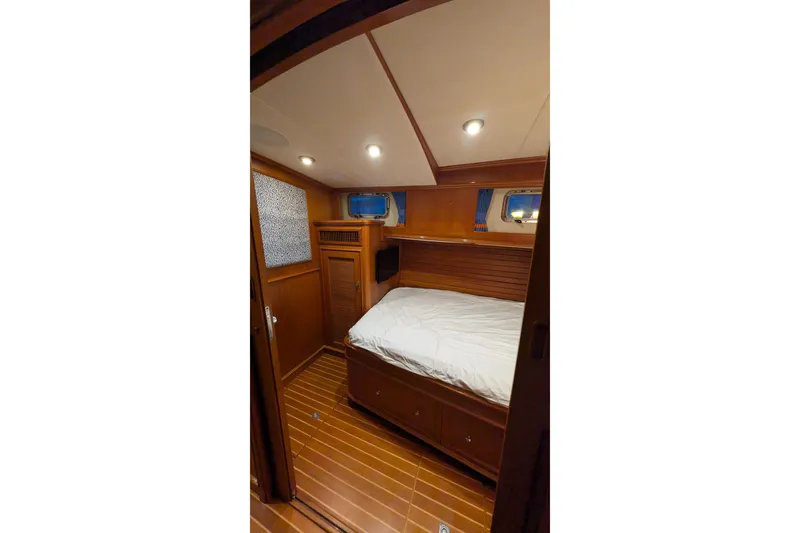 Slide: The Image of Luxurious cabin interior of 2004 Grand Banks 58 Eastbay FB yacht, featuring wood paneling and cozy bed. - 15