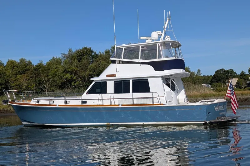 Slide: The Image of 2004 Grandbanks 58 Eastbay FB yacht on calm water, with American flag. - 3