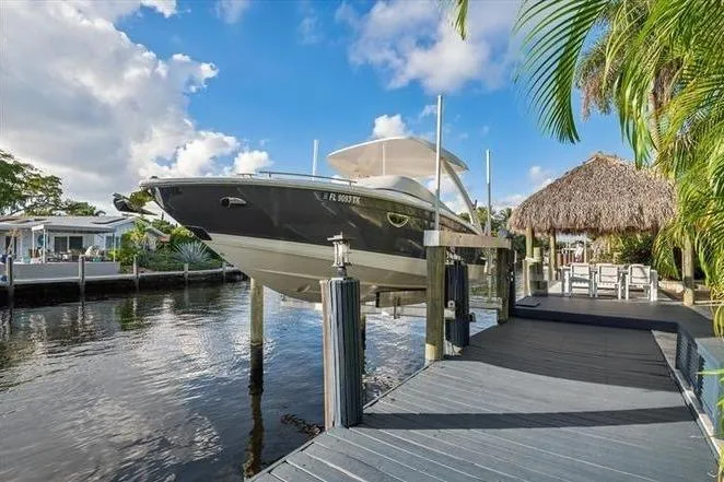 The Image of 2023 Regal LX6 boat docked by a tropical waterfront with palm trees. - 0