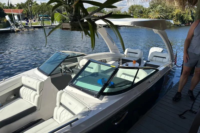 Slide: The Image of 2023 Regal LX6 boat docked by a scenic waterfront, featuring luxurious seating and sleek design. - 2
