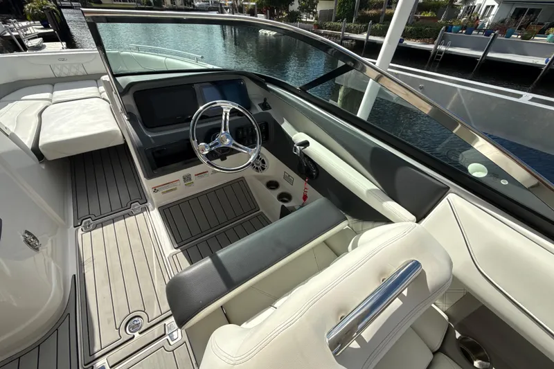Slide: The Image of 2023 Regal LX6 boat interior with steering wheel and seating, docked by the water. - 8