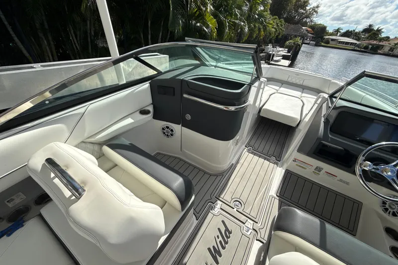Slide: The Image of 2023 Regal LX6 boat interior with luxurious seating and sleek design, docked by a scenic waterway. - 9