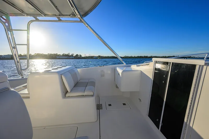 Slide: The Image of 1998 Aura 28 Tournament Series boat interior with seating, overlooking serene water at sunset. - 12