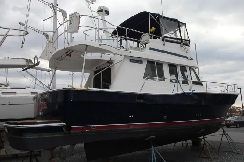 Slide: The Image of 2002 Mainship 390 Trawler docked, rear view with "Gina Lee" nameplate, overcast sky. - 10