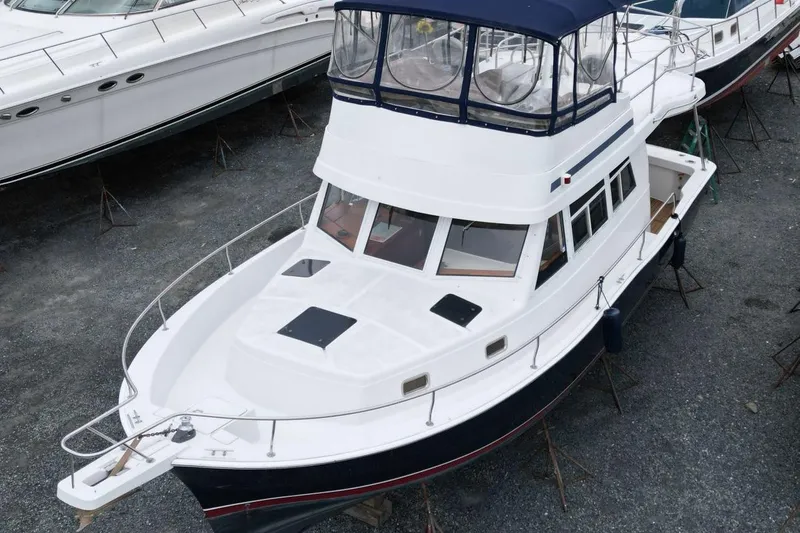 Slide: The Image of 2002 Mainship 390 Trawler boat on stands, cloudy sky background. - 2