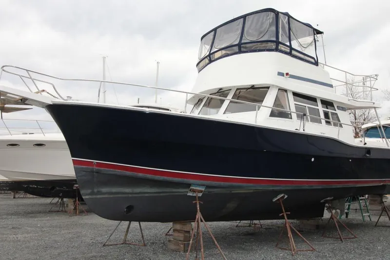 Slide: The Image of 2002 Mainship 390 Trawler docked, rear view with open cabin and visible deck. - 8