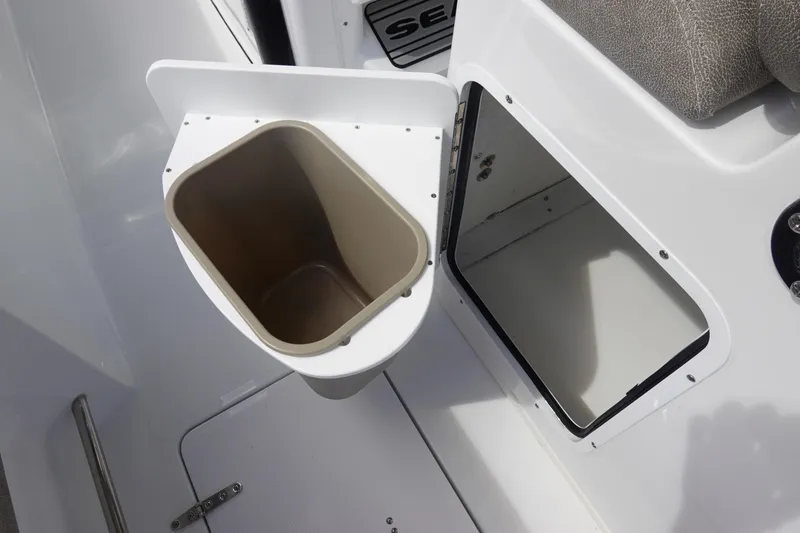 Slide: The Image of 2026 Sea Hunt Gamefish 28 Forward Seating storage compartment with open hatch and trash bin. - 25