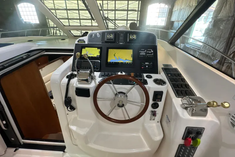 Slide: The Image of 2006 Tiara Yachts 3600 Sovran helm with navigation screens and controls in a bright cabin. - 38