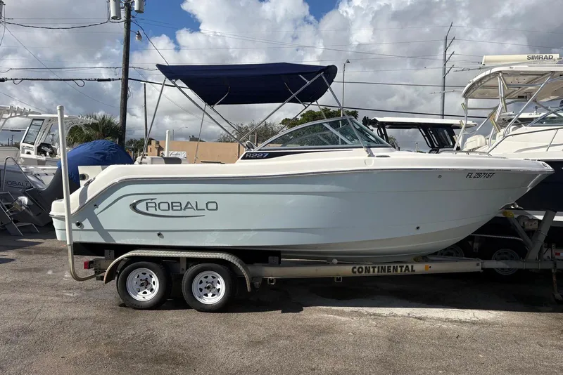 The Image of 2020 Robalo R227 Dual Console boat on trailer, parked outdoors under cloudy sky. - 0
