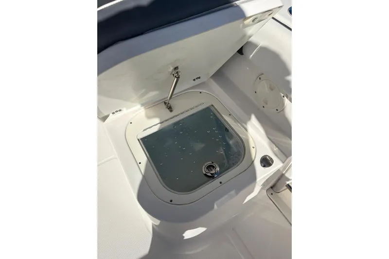 Slide: The Image of 2020 Robalo R227 Dual Console boat storage compartment with open lid and latch. - 13