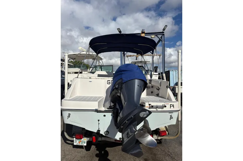 Slide: The Image of 2020 Robalo R227 Dual Console boat with outboard motor, parked under a cloudy sky. - 2