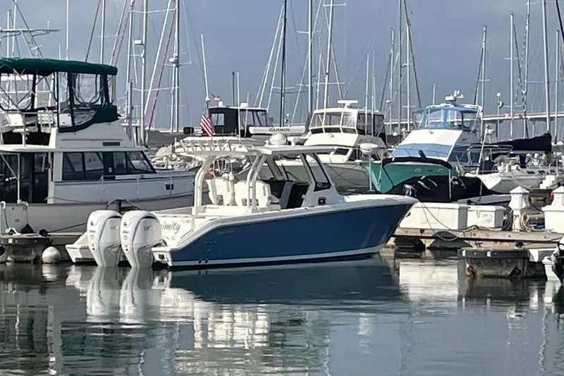 The Image of 2021 Pursuit S 328 Sport boat docked in a marina with other vessels. - 0