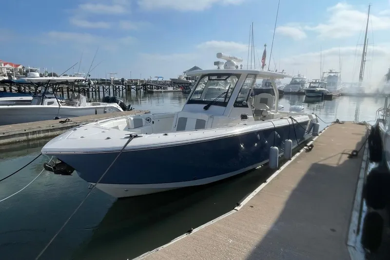 Slide: The Image of 2021 Pursuit S 328 Sport boat docked at a marina under a clear sky. - 3