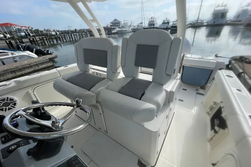Slide: The Image of 2021 Pursuit S 328 Sport boat interior with dual seats and steering wheel at marina. - 31