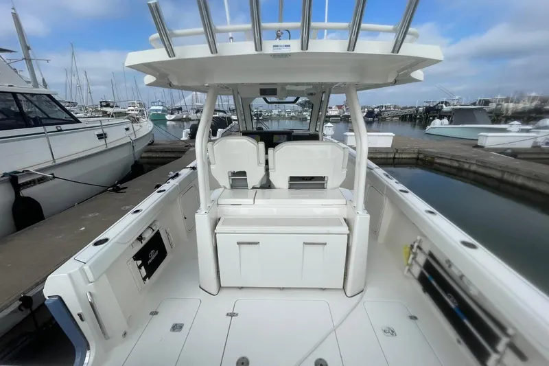 Slide: The Image of 2021 Pursuit S 328 Sport boat interior at marina, showcasing seating and storage. - 32