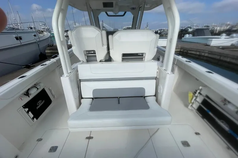 Slide: The Image of 2021 Pursuit S 328 Sport boat interior with seating and docked yachts in background. - 34