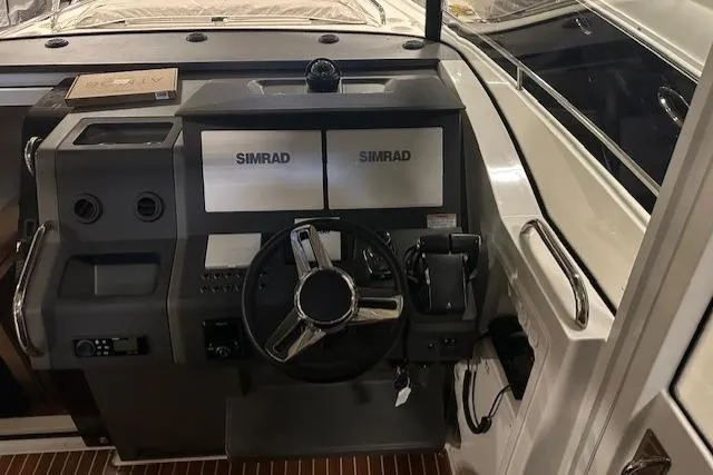 Slide: The Image of 2023 Nimbus C11 boat dashboard with dual Simrad displays and steering wheel. - 15