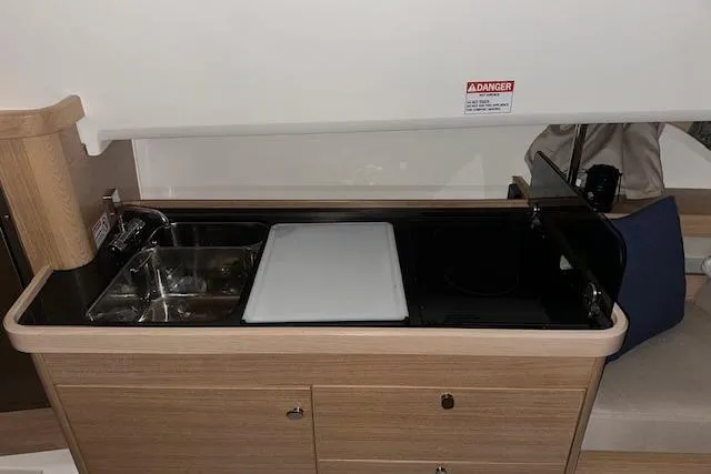 Slide: The Image of 2023 Nimbus C11 kitchenette with sink, cutting board, and stove in compact wooden design. - 18
