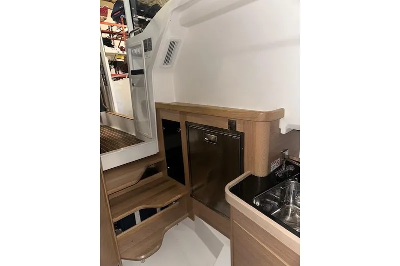 Slide: The Image of Interior of 2023 Nimbus C11 boat featuring wooden cabinetry and compact kitchen area. - 2