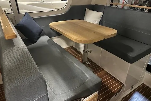Slide: The Image of Cozy seating area in 2023 Nimbus C11 boat with wooden table and cushions. - 20